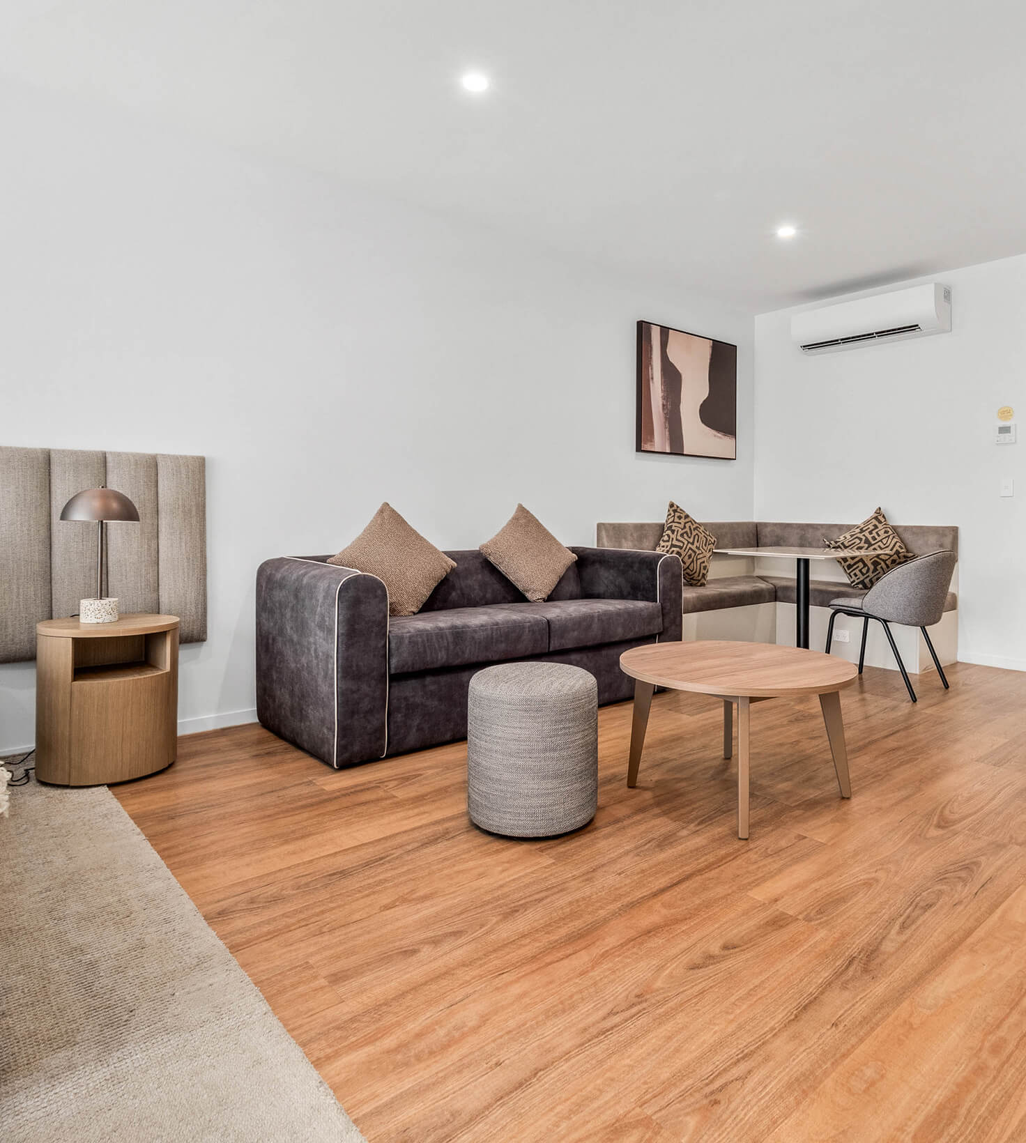 Lounge and dining banquette beside the bedhead in a Deluxe Studio Apartment at Rambla @ Story House