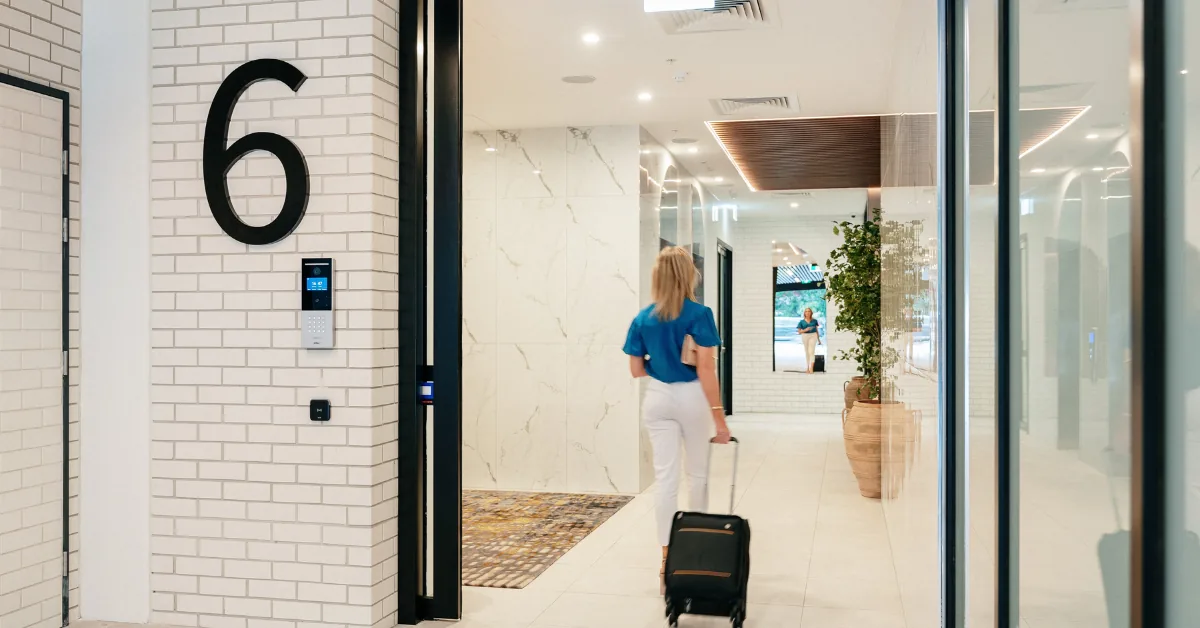 Guest wheeling a suitcase through the entry doors into a bright Rambla lobby