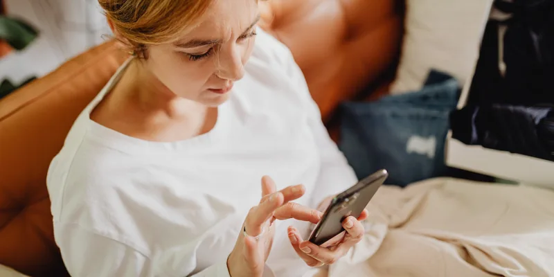 Woman on a couch completing her check-in on her phone before arrival