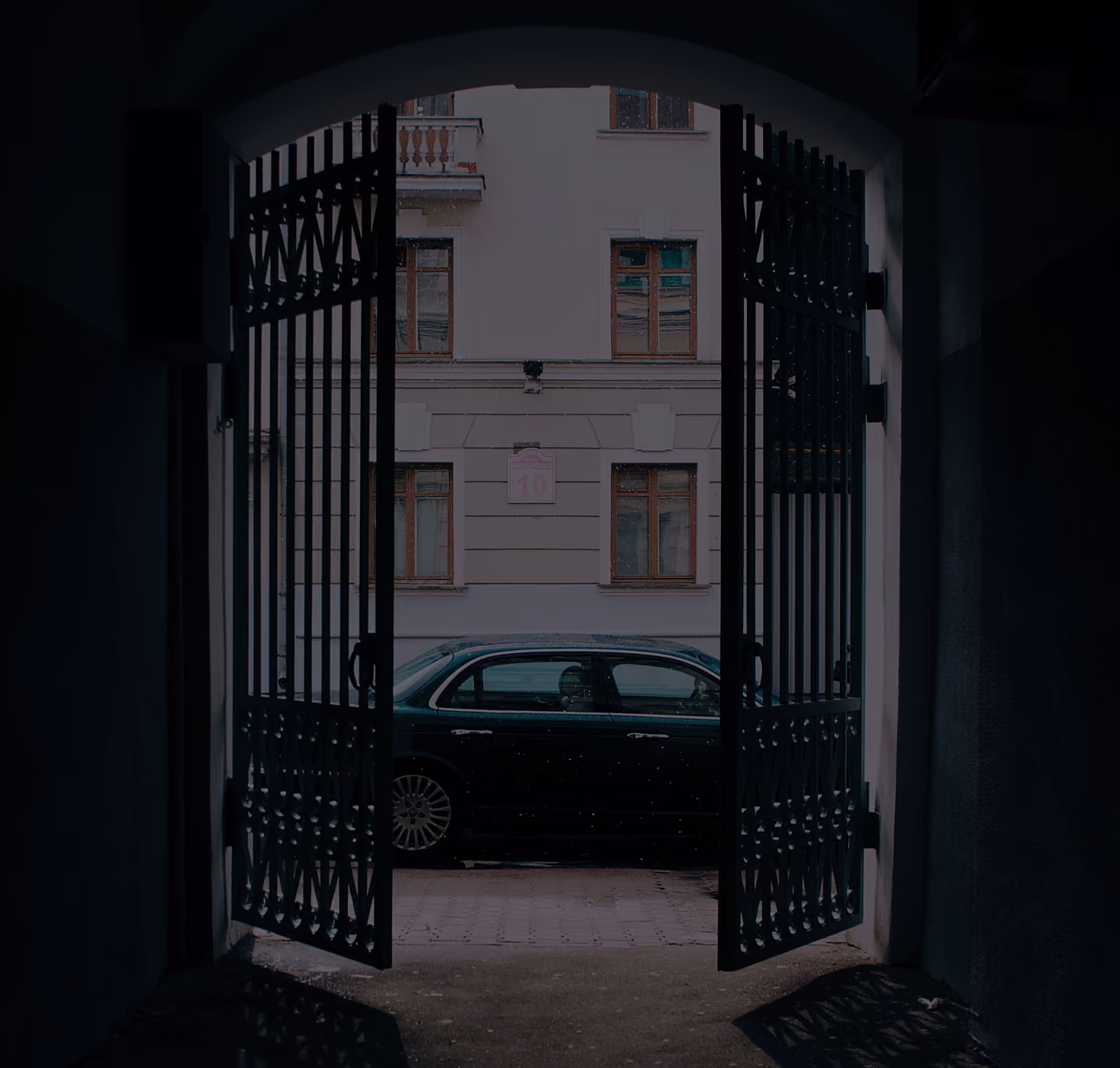 Automatic gates partially opened with a car parked behind them.