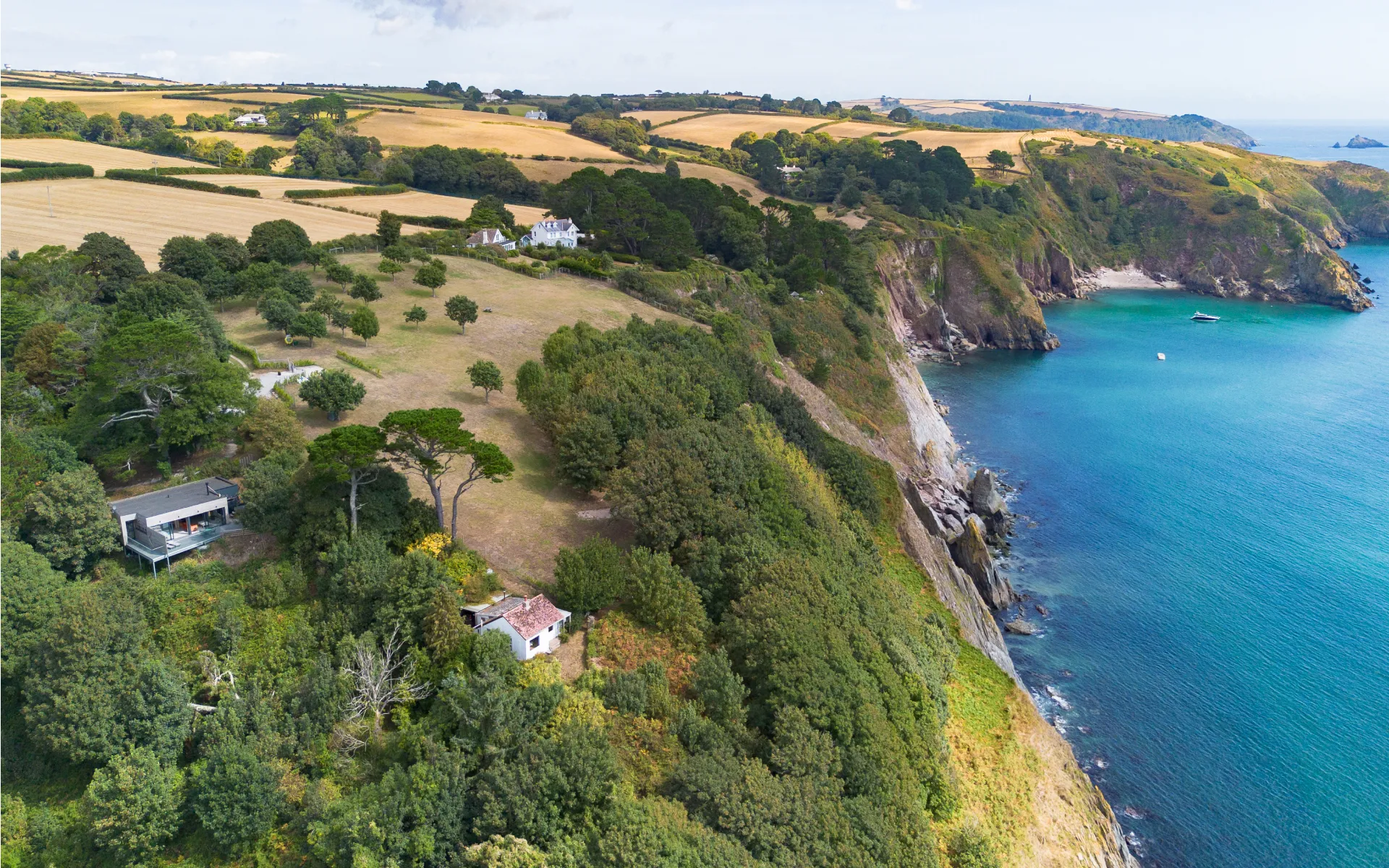 An aerial view of a house on a cliff overlooking the ocean.