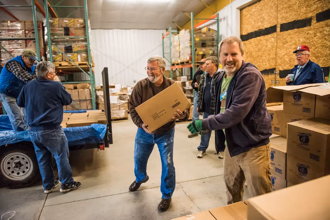 Workers moving boxes in a warehouse, smiling and collaborating