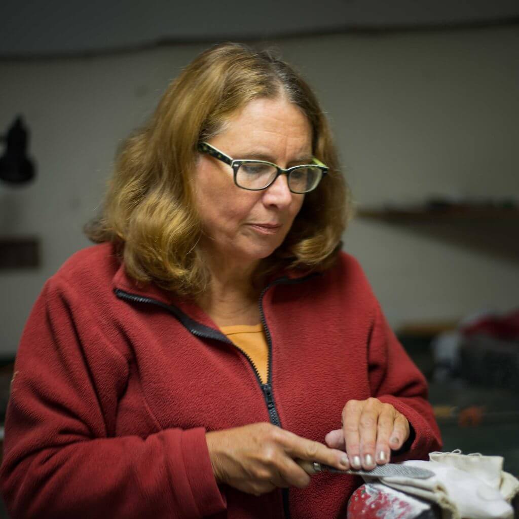 Woman in red fleece working on a craft project with focused expression