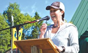 Smiling speaker at podium giving speech outdoors on sunny day