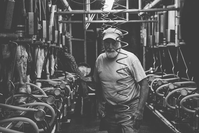Elderly worker standing in industrial workshop surrounded by machinery