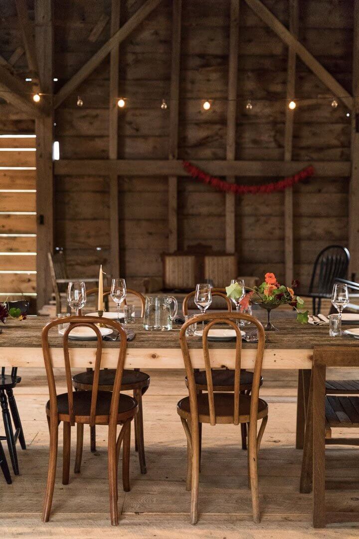 Rustic wooden barn interior with elegantly set dining table and hanging lights