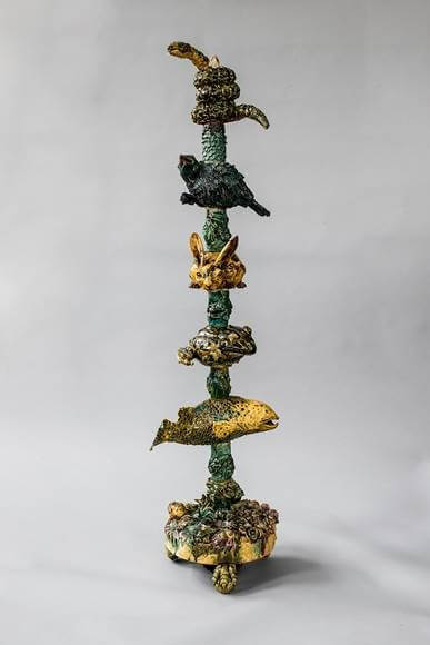 Tall ceramic sculpture with stacked, twisted animal-like forms in green and gold