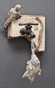 Metallic birds perched on vintage water spigot mounted on textured background