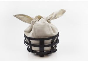 Cream-colored fabric tied in a knot inside a dark metal wire basket