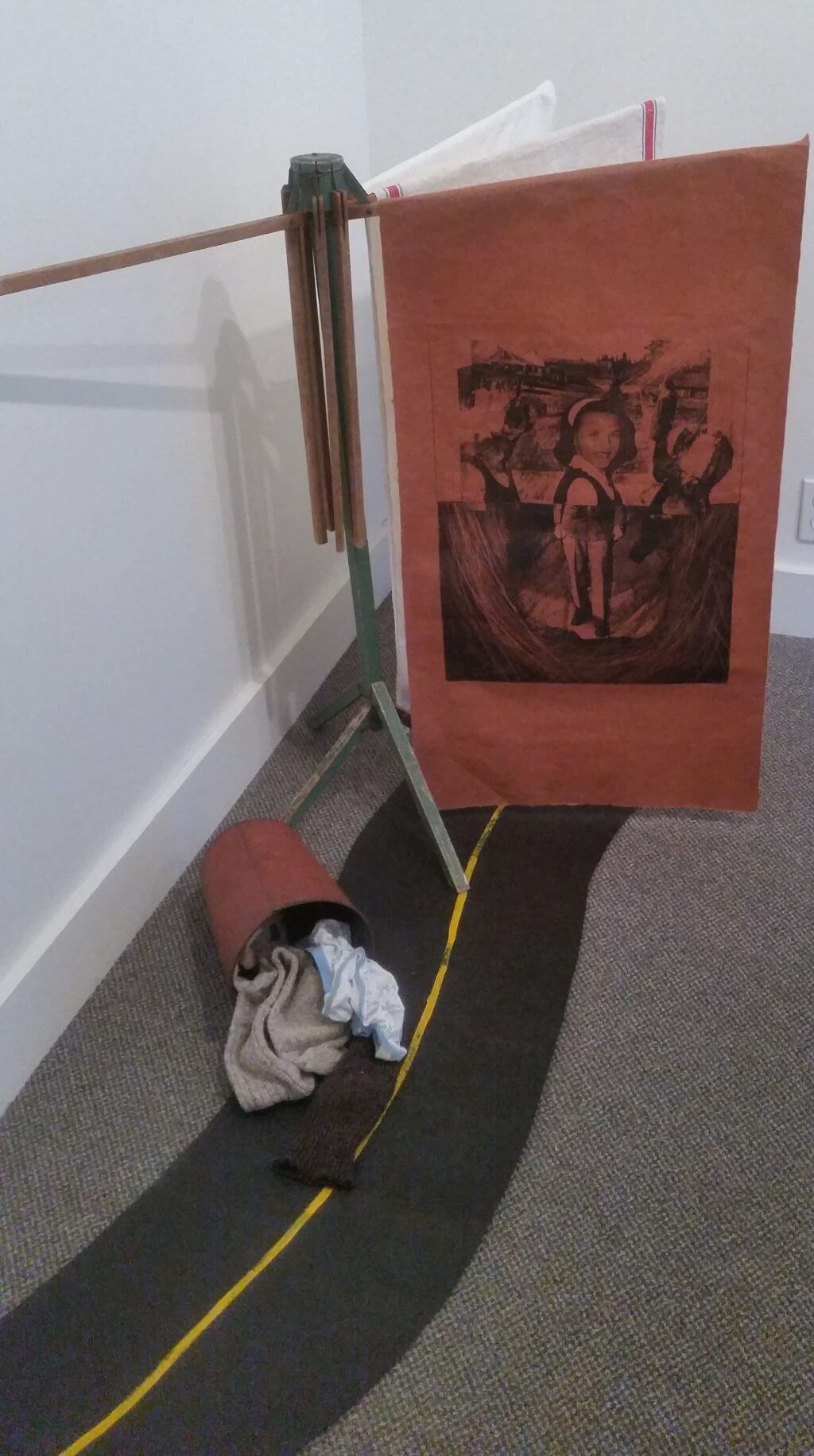 Art print on stand with yellow tape, rags, and textured floor