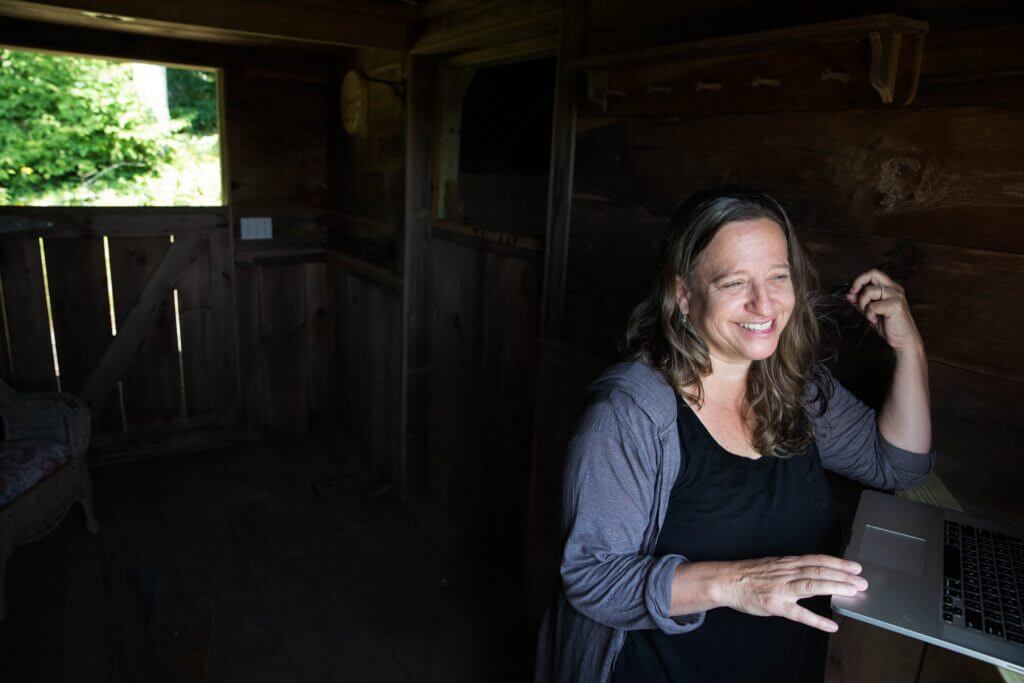 Smiling woman working on laptop in rustic wooden interior with natural light