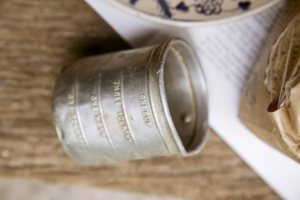 Vintage metal measuring cup with measurement markings on wooden surface