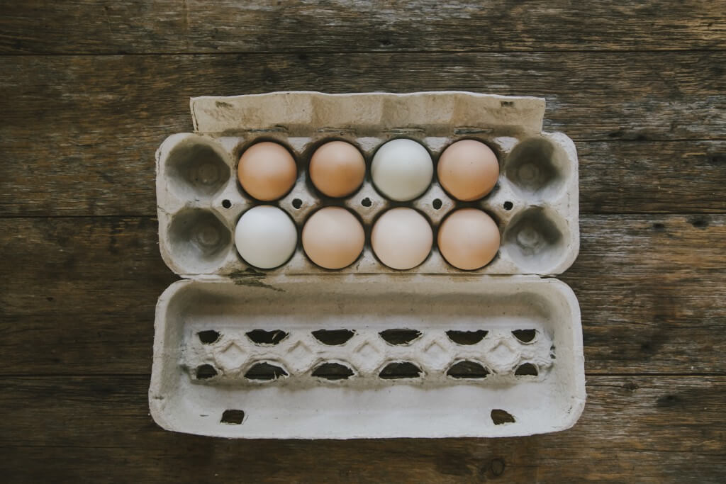 Egg carton with brown and white eggs on wooden background