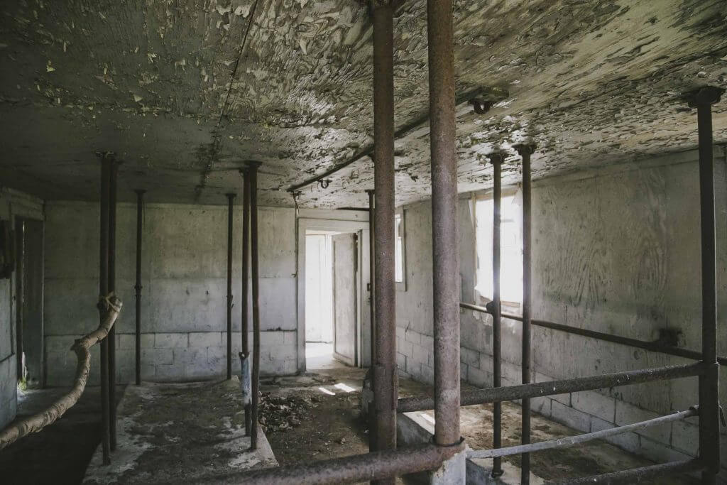 Abandoned interior with rusty metal supports and decaying walls