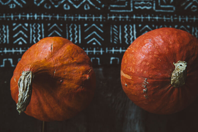 Two ripe orange pumpkins with textured skin against geometric background