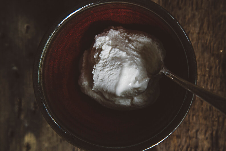 Scoop of vanilla ice cream in a dark red ceramic bowl
