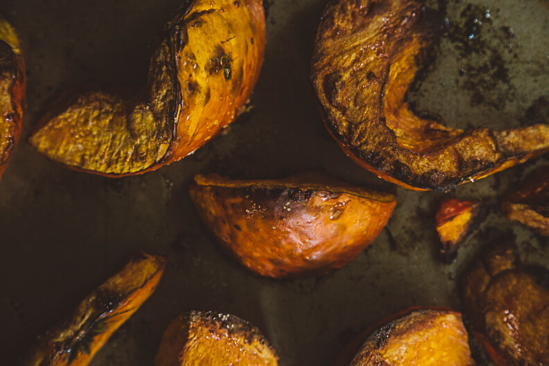 Roasted golden-brown pumpkin or squash chunks in dark skillet