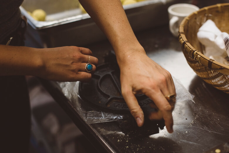 Hands preparing food on a dusty surface with cooking ingredients nearby