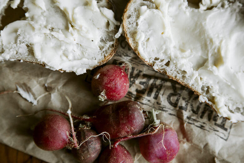Fresh radishes and bread with creamy spread on rustic background