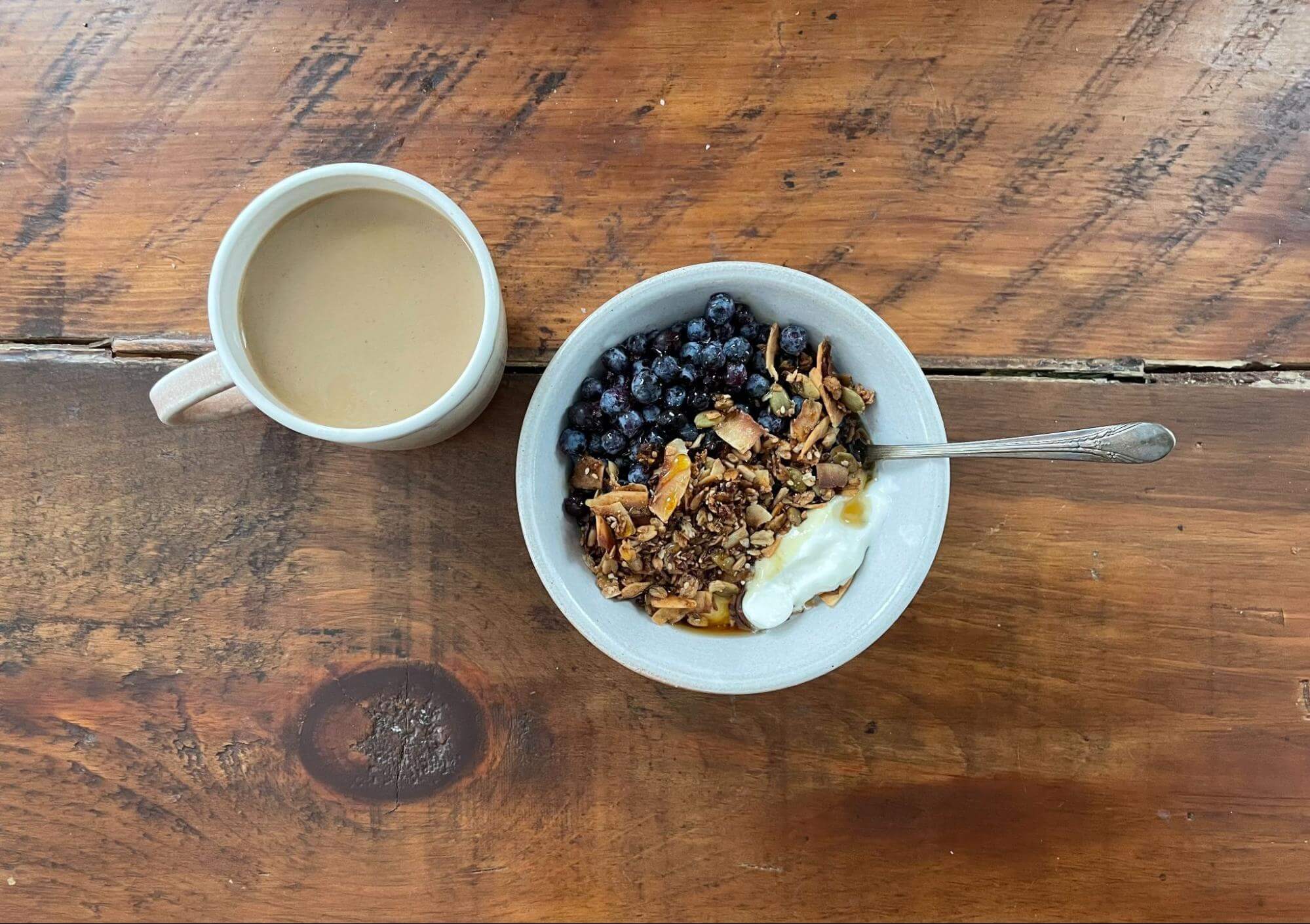 Granola with blueberries, yogurt, and coffee on rustic wooden table