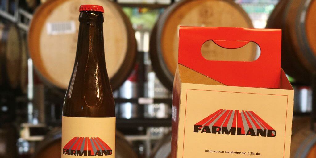 Farmland beer bottle and packaging with wooden barrels in background