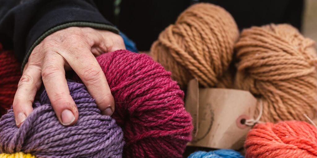 Hand touching colorful yarn balls for knitting or crafting project