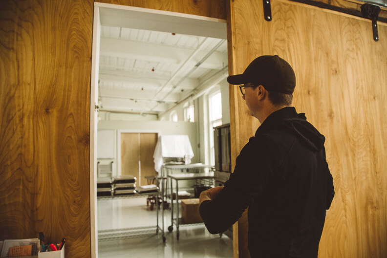 Person in black opens door to industrial kitchen or workspace