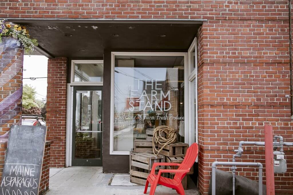 The Farm Stand storefront with red chair, wooden crates, and brick exterior
