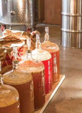 Glass fermentation jugs with brewing ingredients in a winery or brewery
