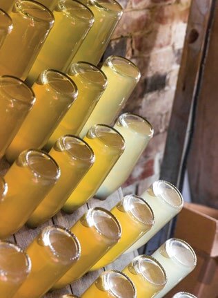 Rows of yellow and white glass bottles stacked on a rustic shelf