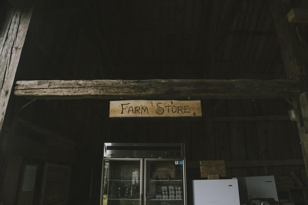 Rustic wooden "Farm Store" sign above refrigerators in dimly lit space