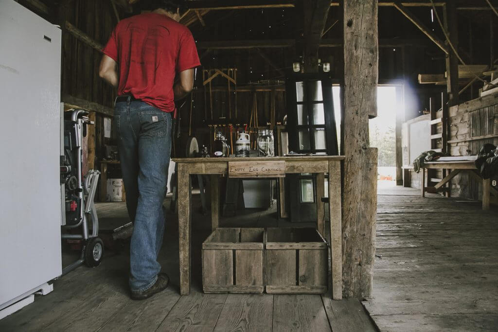 Person standing in rustic wooden workshop with wooden storage boxes