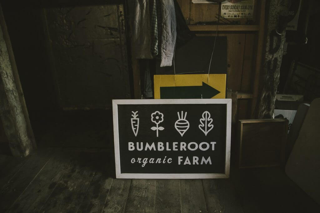 Bumbleroot Organic Farm sign with vegetable icons in rustic wooden interior