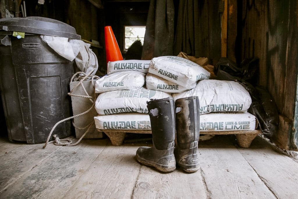 Stacked Alldale lawn and garden bags, boots, and trash can in shed