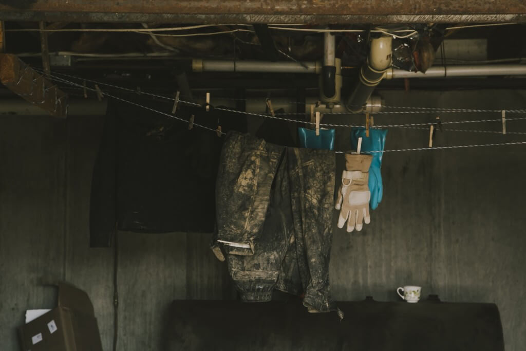 Camouflage jacket and gloves hanging to dry on clothesline in basement