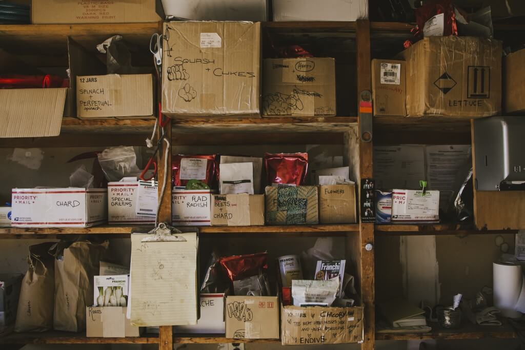 Cluttered shelves with cardboard boxes, seed packets, and shipping labels