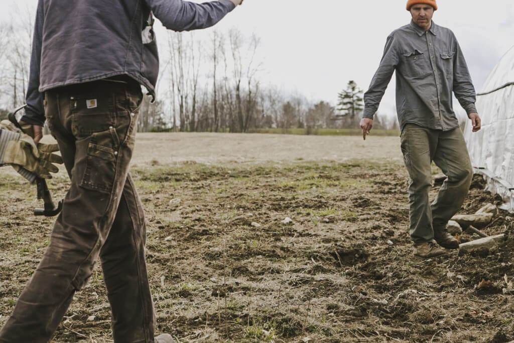 Two workers in work clothes standing on muddy agricultural field