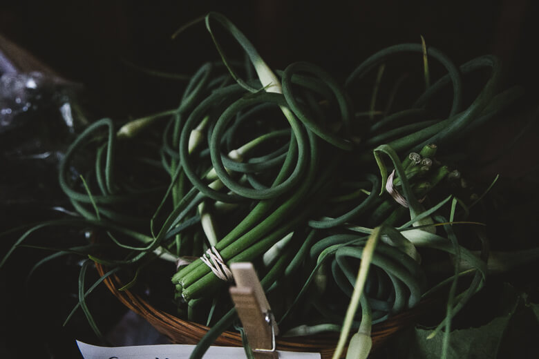 Fresh green garlic scapes tangled in a wooden basket