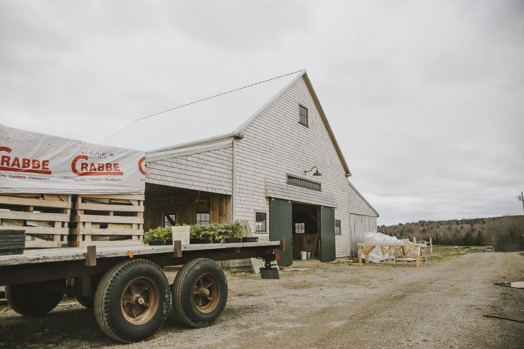 Crabbe lumber warehouse with trailer, plants, and wooden barn