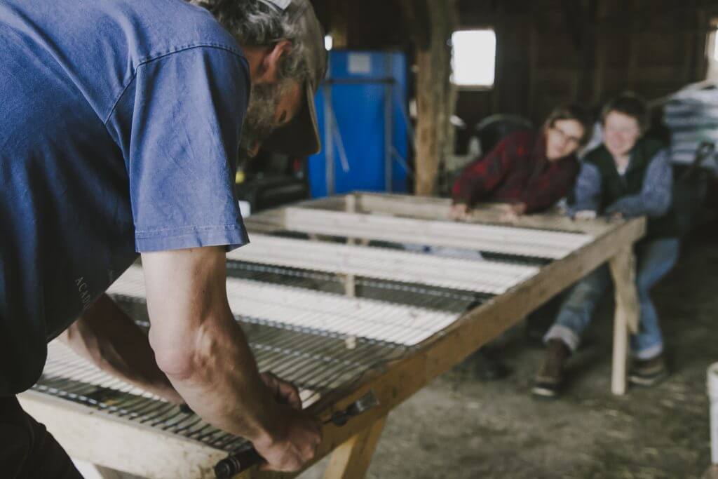 Workers processing materials on large wooden sorting table in workshop