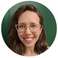 Smiling woman with glasses wearing brown hair against green background