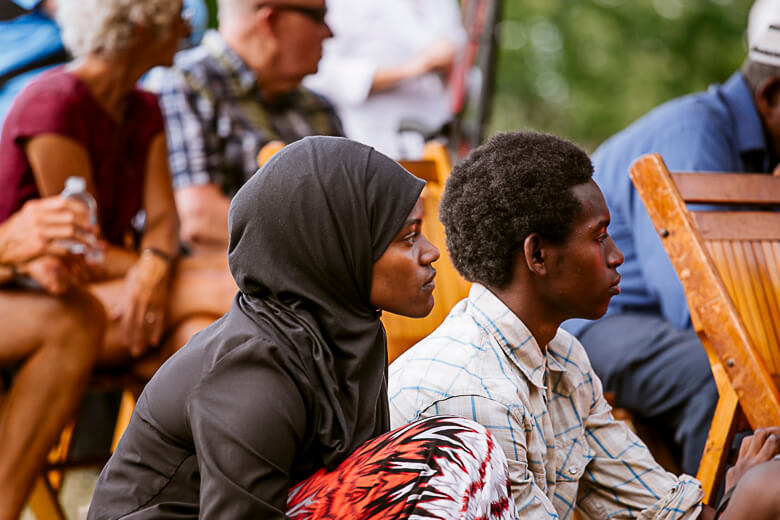 People sitting together outdoors, woman in hijab and man in plaid shirt