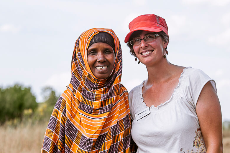 Two women smiling together, wearing colorful traditional and casual clothing