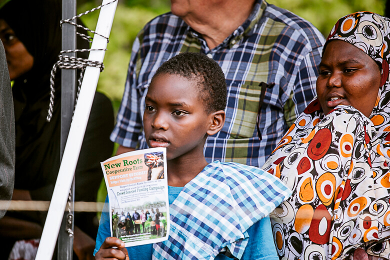 Young person holding New Root Cooperative newsletter at community event