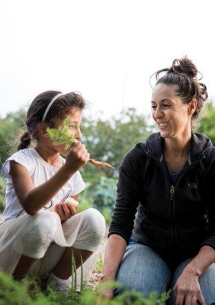 Mother and daughter gardening together, smiling and enjoying nature