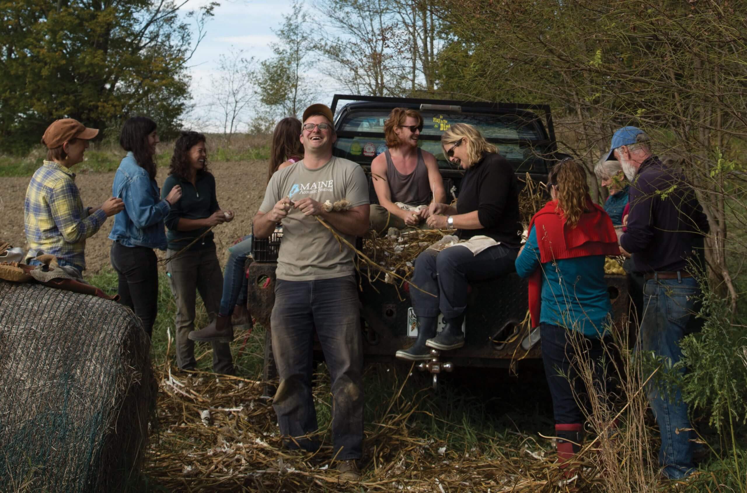 Group of people working together near truck in rural field during harvest