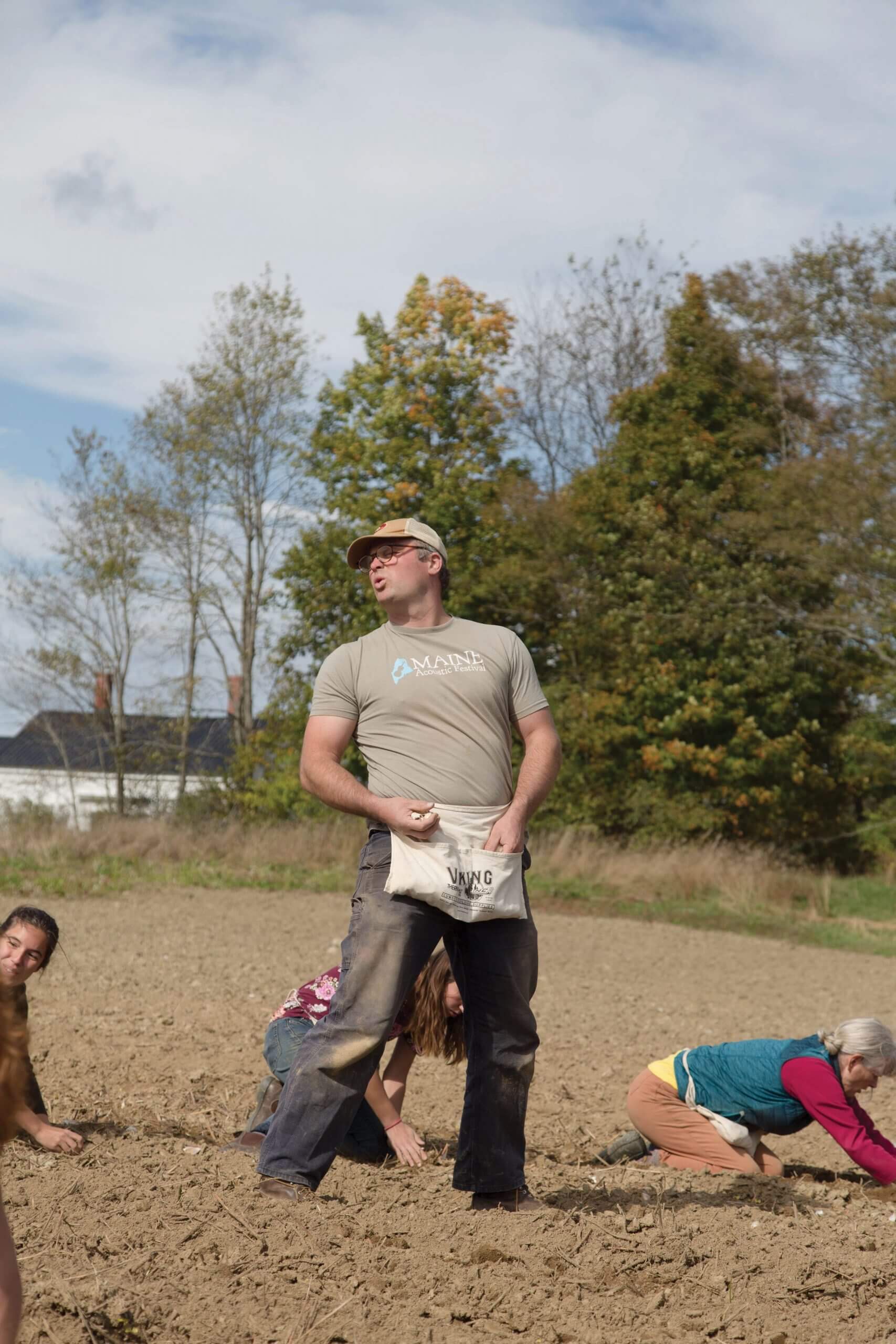 Archaeological dig team working in field with trees in background