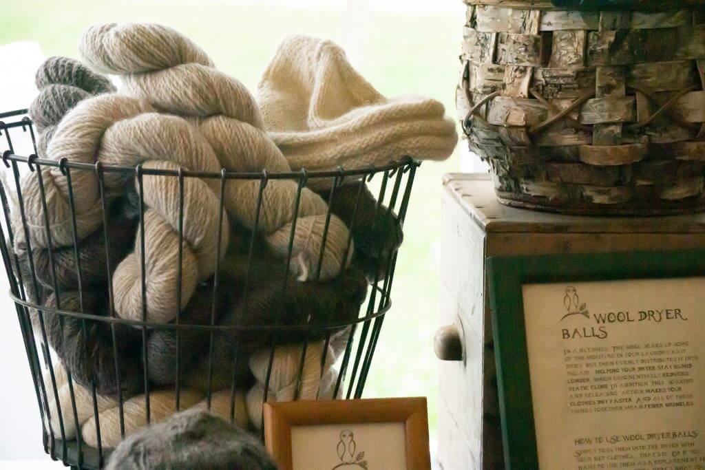Wool yarn skeins in wire basket with wool dryer balls instructions