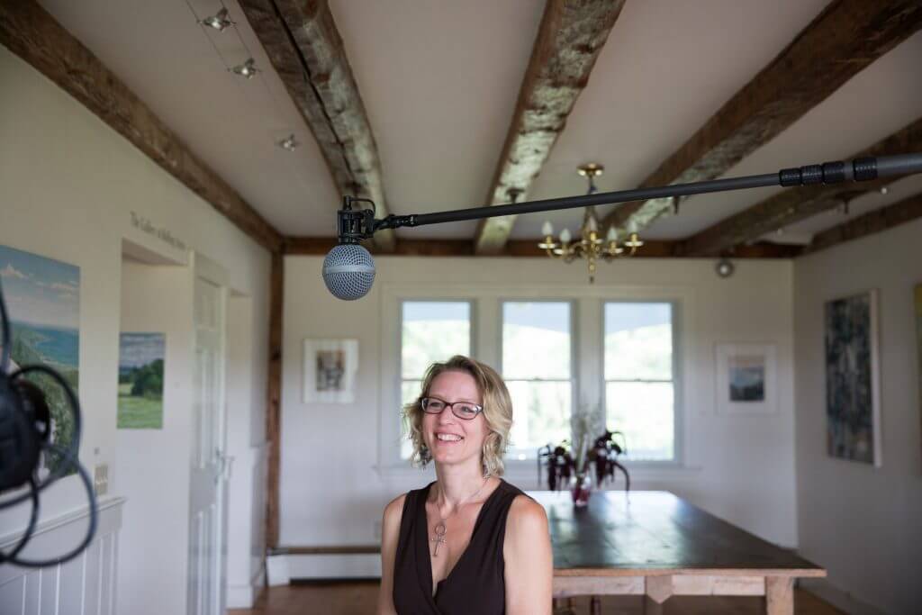 Woman standing in rustic room with microphone overhead and wooden beams