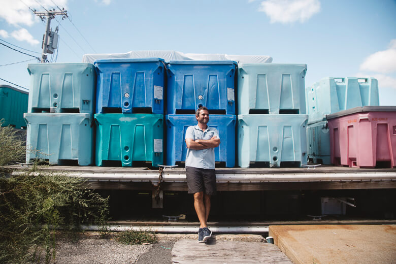 Worker standing in front of stacked blue and teal portable toilets
